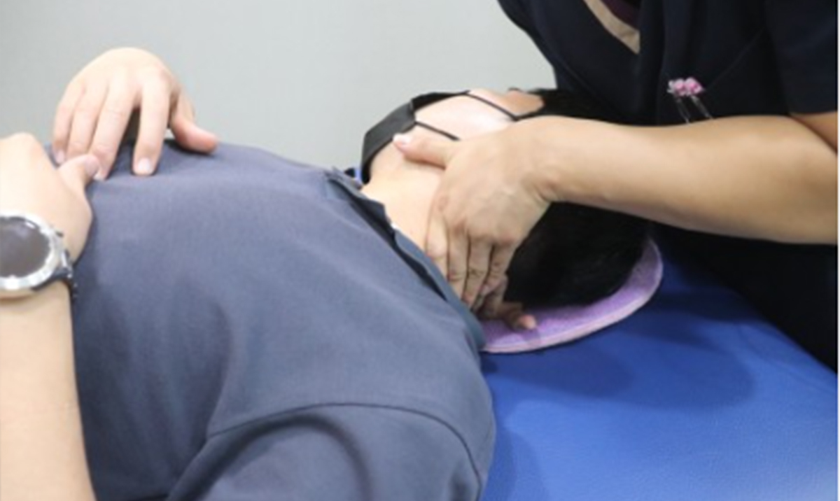 치료사가 목과 어깨를 손으로 풀어 주는 도수치료 장면